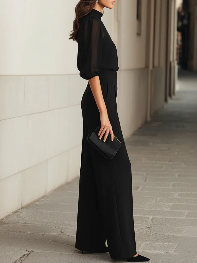 Completo Nadie nero di profilo, con pantalone ampio e pochette